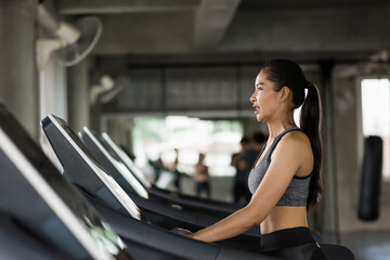 Fototapeta na wymiar Asian young woman walk and run on treadmills in fitness gym