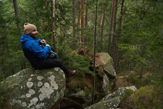 Happy traveler sitting on the rock in forest