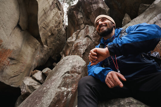 Positive delighted hiker having rest on rock