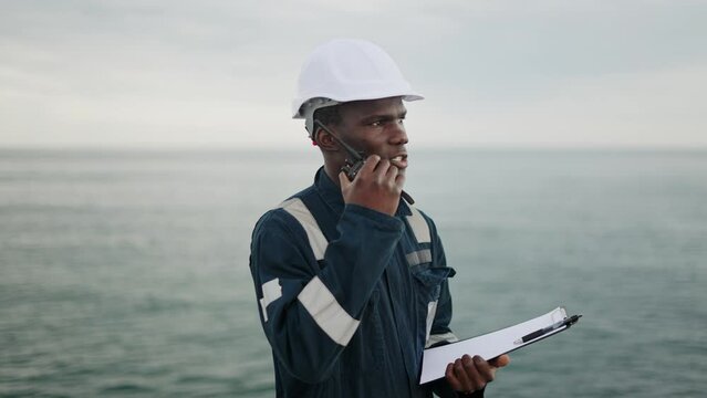 Serious maritime worker speaking on walkie talkie