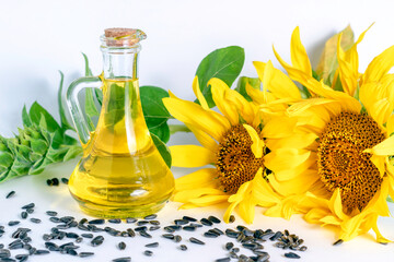 Bottle of sunflower oil and sunflower flowers with seeds on a white background