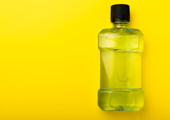 Mouthwash bottle. Rinse for oral hygiene on a yellow background. Mouthwashes help get rid of bad breath, cavities, and plaque. Product for dental care. Top view. Assortment