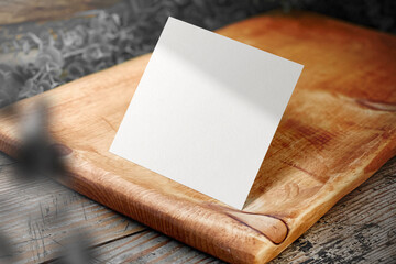 Clean minimal square flyer mockup standing on wooden plate with leaves
