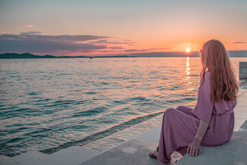 Woman listening to the sound of the waves at the sea organ in Zadar.
