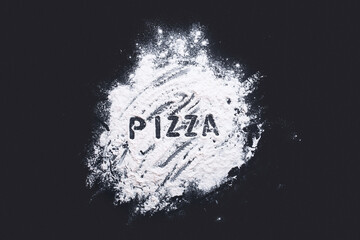 White flour on a dark tabletop with the inscription Pizza