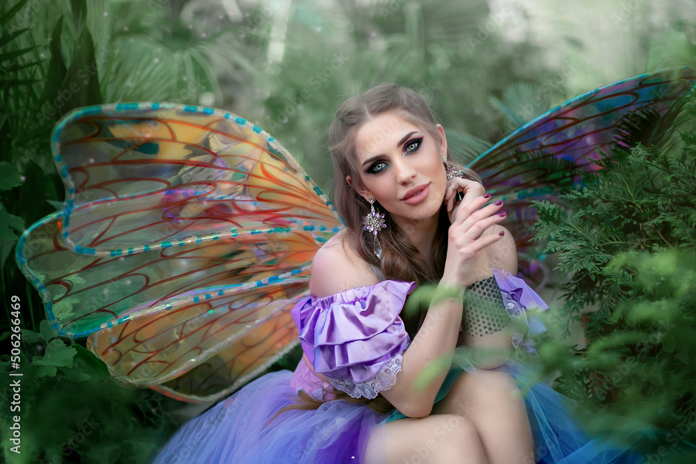 Wall mural a beautiful woman is a little cute fairy with butterfly wings in a green exotic forest. fantasy shoo