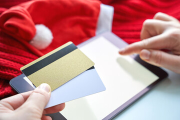 Plastic credit card mockup and tablet. Color red and white background. Atm empty debit payment. Currency shopping with stripe. Christmas hat. new year concept mockup. Hand holding