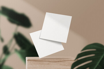 Clean minimal square flyer mockup floating on wooden block with leaves