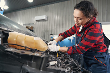 Young worker using screwdriver while repairing motor vehicle