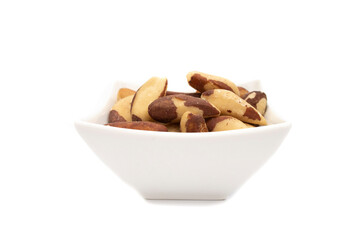 A white bowl with brazil nut or amazon nut, isolated on white background. Bertholletia excelsa is a tree of the Lecythidaceae family, native to South America, endemic to the Amazon.