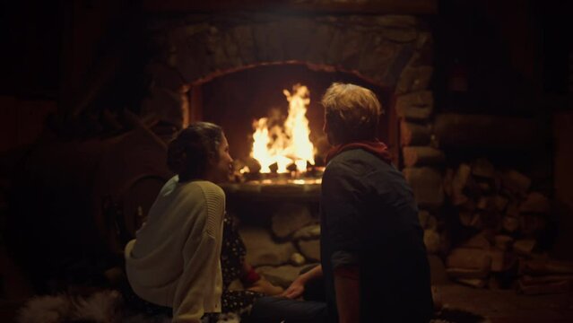 Romantic couple sitting fireplace in country house. Two lovers enjoy cozy home.