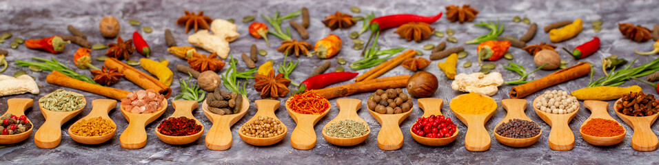 A set of spices on a gray background. Variety of spices from India. Food decoration design. Various spices, peppers and herbs close-up top view. Set of peppers, salt, herbs and spices for cooking.