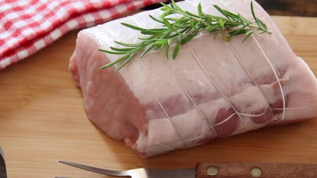 piece of raw pork meat with rosemary ready for baking, video