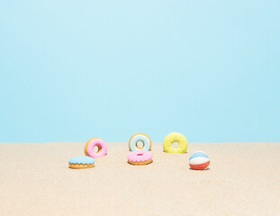 Colorful donuts in the beach sand. Summertime. Holiday or summer vacation composition.