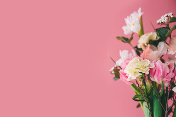 beautiful bouquet of carnations, peony tulips, roses and daffodils on a pink background, copy space