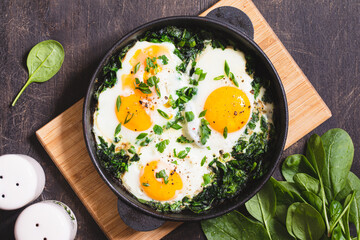 green shakshuka in a cast iron skillet. fried eggs with spinach and fried toast. healthy nutritious breakfast