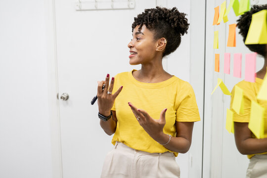 african american woman, businesswoman in a meeting in office writing down tasks on post-it