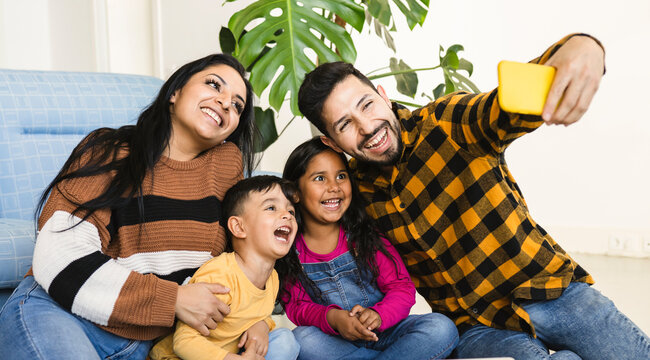 happy hispanic family taking a photo with smartphone in home