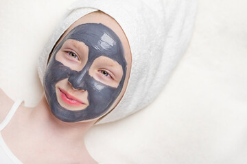 Charcoal mask on the girl's face on a light background.