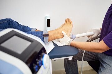 Shock wave therapy of the heel spur. Physiotherapist doctor uses medical equipment for highly...