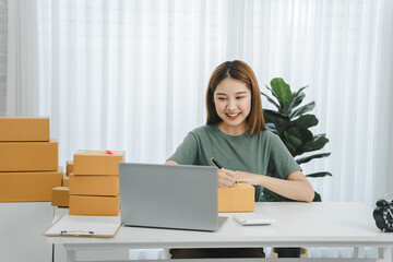 Portrait of a Small Business Startup, SME Owner, Female Entrepreneur work on parcel boxes Receipts and check orders online to prepare boxes. Selling to customers. Online SME business idea.