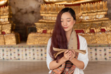 portrait young asian woman wearing traditional dress of Thailand reading Sanskrit ancient Tripitaka...