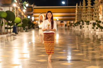 Portrait asian buddhist woman wearing traditional dress of Thailand holding candle and walking around at Wat Suthat Thepwararam