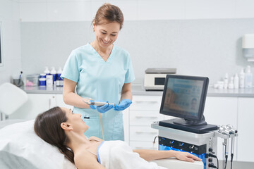 Female cosmetologist performing hydrafacial treatment in clinic