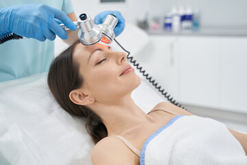 Woman having face lifting procedure in beauty salon