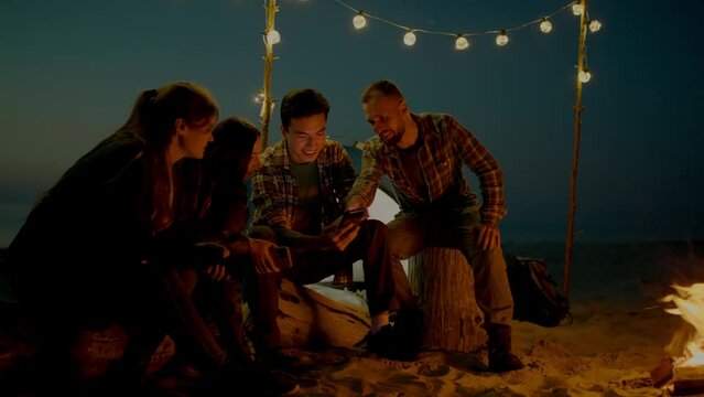 Group of young people having camp on the beach at night