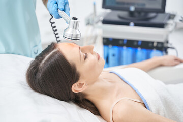 Woman having radiofrequency lifting procedure in beauty salon