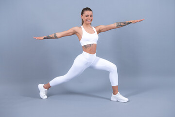 Full body of young cheerful smiling woman in sports wear, isolated over gray background. Healthy beautiful sportswoman.
