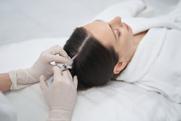 Doctor hands doing injection into woman scalp in beauty salon - obrazy, fototapety, plakaty