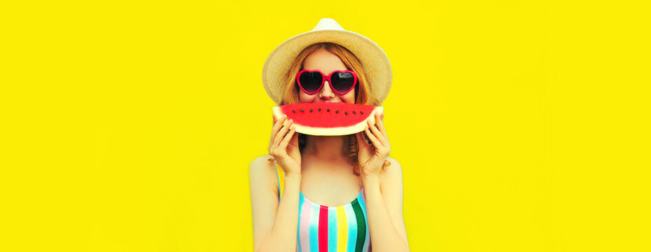 Summer portrait of happy smiling woman with fresh slice of watermelon wearing straw hat, red heart shaped sunglasses on yellow background, blank copy space for advertising text
