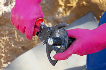 Elektriker mit Sicherheitshandschuhen bearbeitet Erdkabel für den Hausanschluss