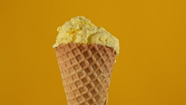 Banana ice cream rotating at yellow background. Yummy yellow ice cream. Food concept. Close-up in 4K, UHD