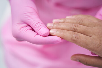 Doctor in pink sterile gloves is holding female hand