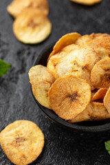 Dried banana chips, snack in rustic coconut bowl