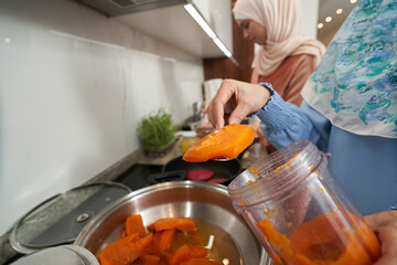 Female hand placing food into frying pan