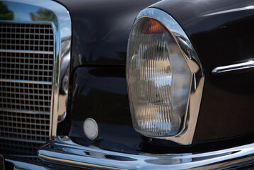 Headlight of a classic, vintage car from 60s in a sunny day