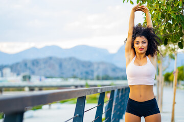 fit and sporty young latin hispanic woman doing stretching in city park