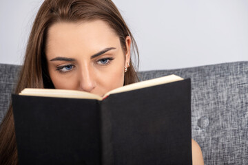 Leisure and hobbies concept. Portrait of beautiful brunette woman with blue eyes reading book. Book...