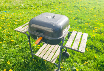 Beautiful metal barbecue grill closed on the lawn on a summer day. Black weber for outdoor cooking