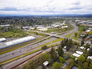 Shooting from a drone. Large highway, traffic near the green town. A mountain range is visible in the distance. Cloudy sky. Ecology, environmental protection, construction, planning, infrastructure.
