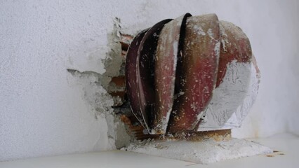 4k Video. Old and faded rotary shaft chimney aspirator on the roof. Red and corrosive  and plaster reminings on it with plastered wall background.