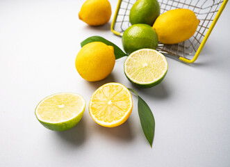 Fresh lemons and limes fall out of  a supermarket basket on a blue background. Citrus fruit concept for freshly squeezed lemonade