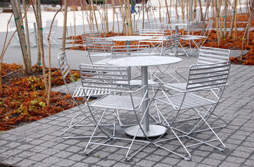 Tables and chairs under the rain on a concrete tile floor on a cloudy day