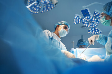 Couple of surgeons making laparoscopic operation in medical center