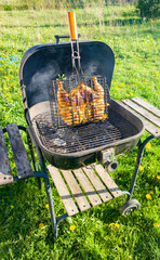 Cooking grilled chicken outdoors in a grill on a bbq grill. Steel metal grill cooking outdoors