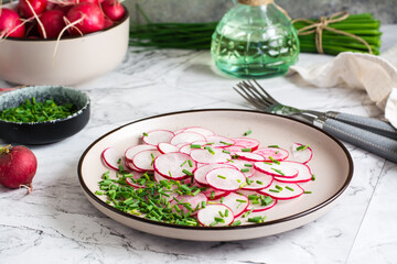Fresh radish and green onion salad on a plate on the table. Vegetarian vitamin vegetable diet.
